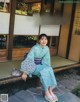 A woman in a blue kimono sitting on a bench.