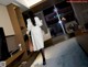 A woman in a white coat is walking through a hotel room.