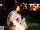 A woman sitting next to a fire pit at night.