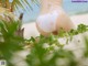 A woman in a white bikini sitting on a beach.