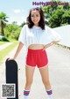 A young woman holding a skateboard on the side of a road.