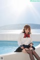 A woman sitting on the edge of a swimming pool.