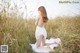 A woman in a white dress sitting in a field.