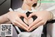 A woman making a heart shape with her hands.