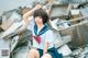 A woman in a school uniform sitting on top of a pile of rubble.