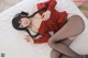 A woman in a red sweater and black stockings laying on a bed.