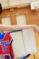 A young girl holding up a basketball jersey with the number 1 on it.