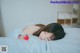 A woman laying on a bed with a strawberry in her hand.