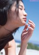 A woman with her eyes closed on the beach.