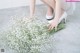 A woman in white shoes holding a bunch of baby's breath.