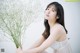 A woman in a white dress holding a bunch of flowers.